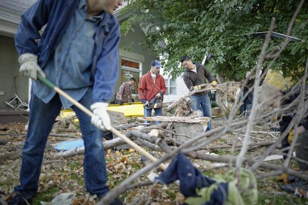 Los hombres jóvenes ayudan a limpiar las ramas de el patio de alguien. Imagen a través de LDS Media Library